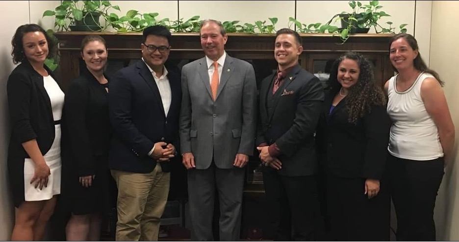 Students posing with Tom Udall in front of a cabinet