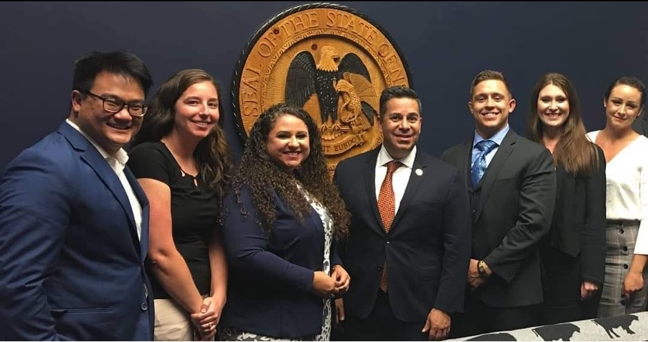 Students posing with Ben Ray Lujan in front of an official seal