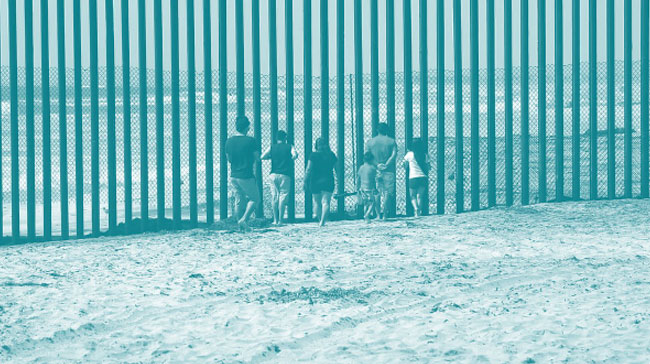 A photo of a group of children standing at the border wall