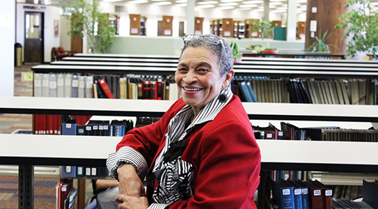 Marsha Hardemen, older woman of color sitting at a desk in a library