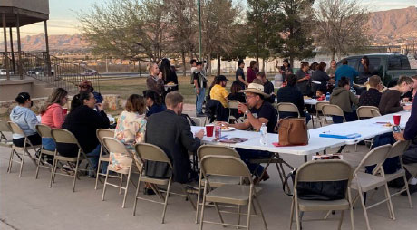 Photo of a group gathered eating in park area.