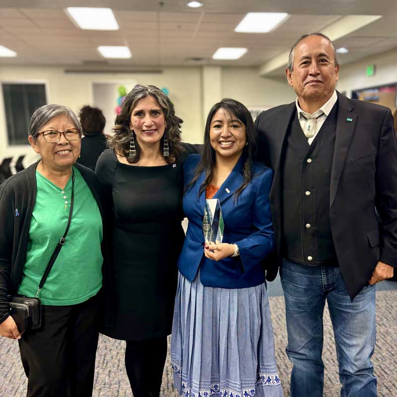 Group of people standing together with one holding an award.