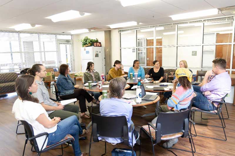 Group of students and instructors around a table having a discussion